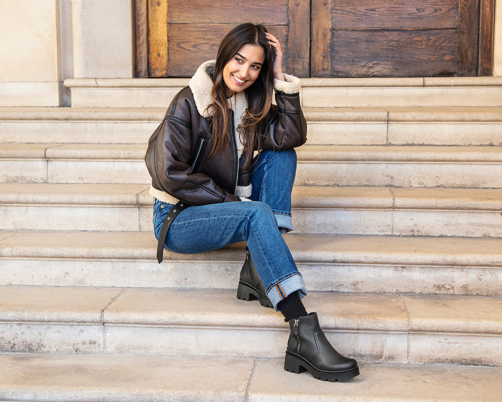 Chica con botas con tacón sentada en una escalera